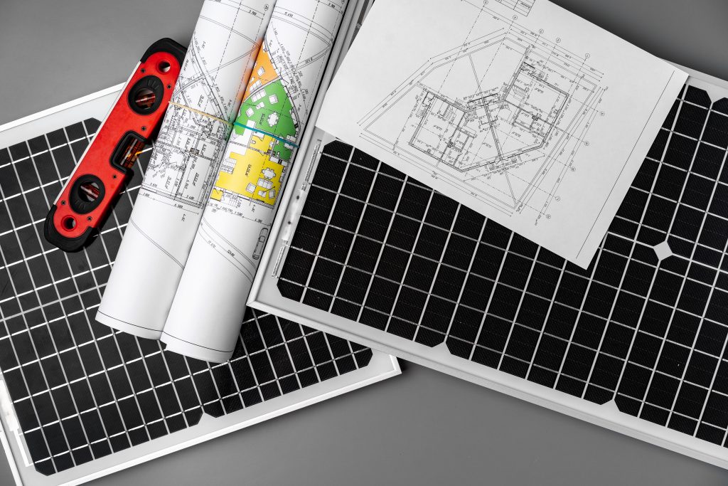 Architectural blueprints and solar panel on table close up