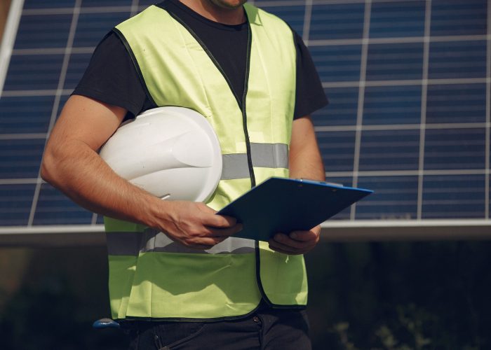 Engineer in a white helmet. Man near solar panel. Worker with a folder.